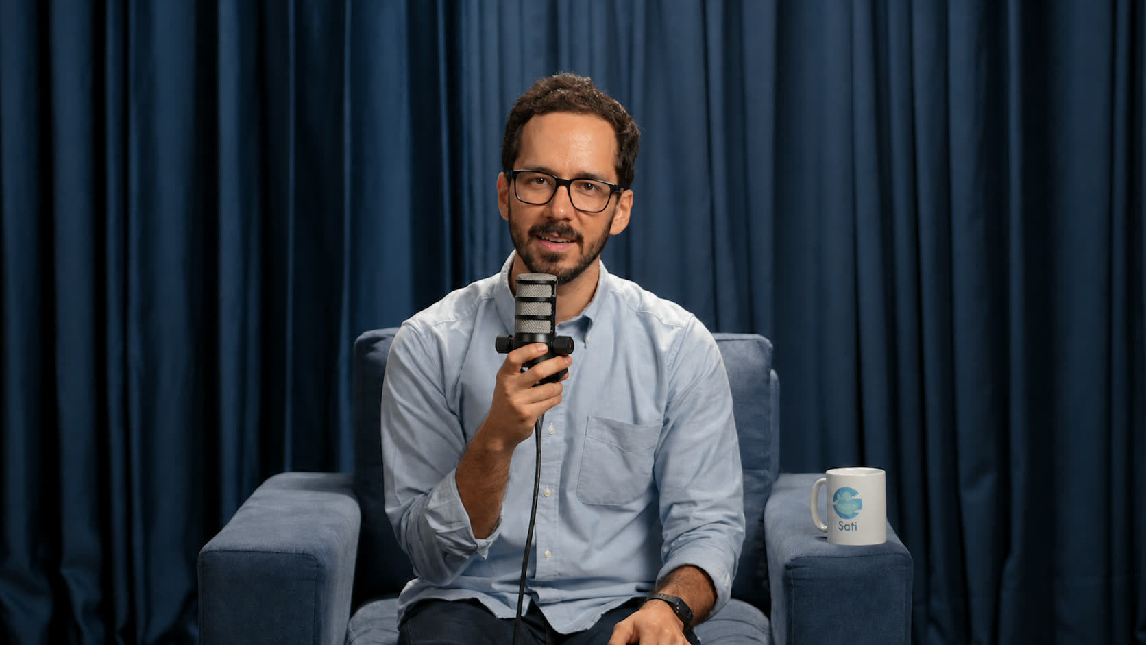 Fernando Andía sentado, con un micrófono en la mano, grabando un video